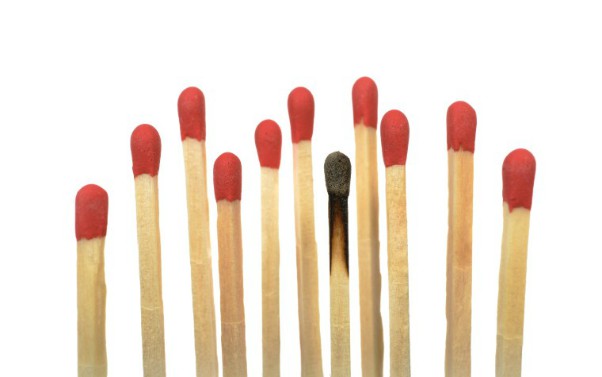 Row of upright red-tipped matches with one burned match in the center.